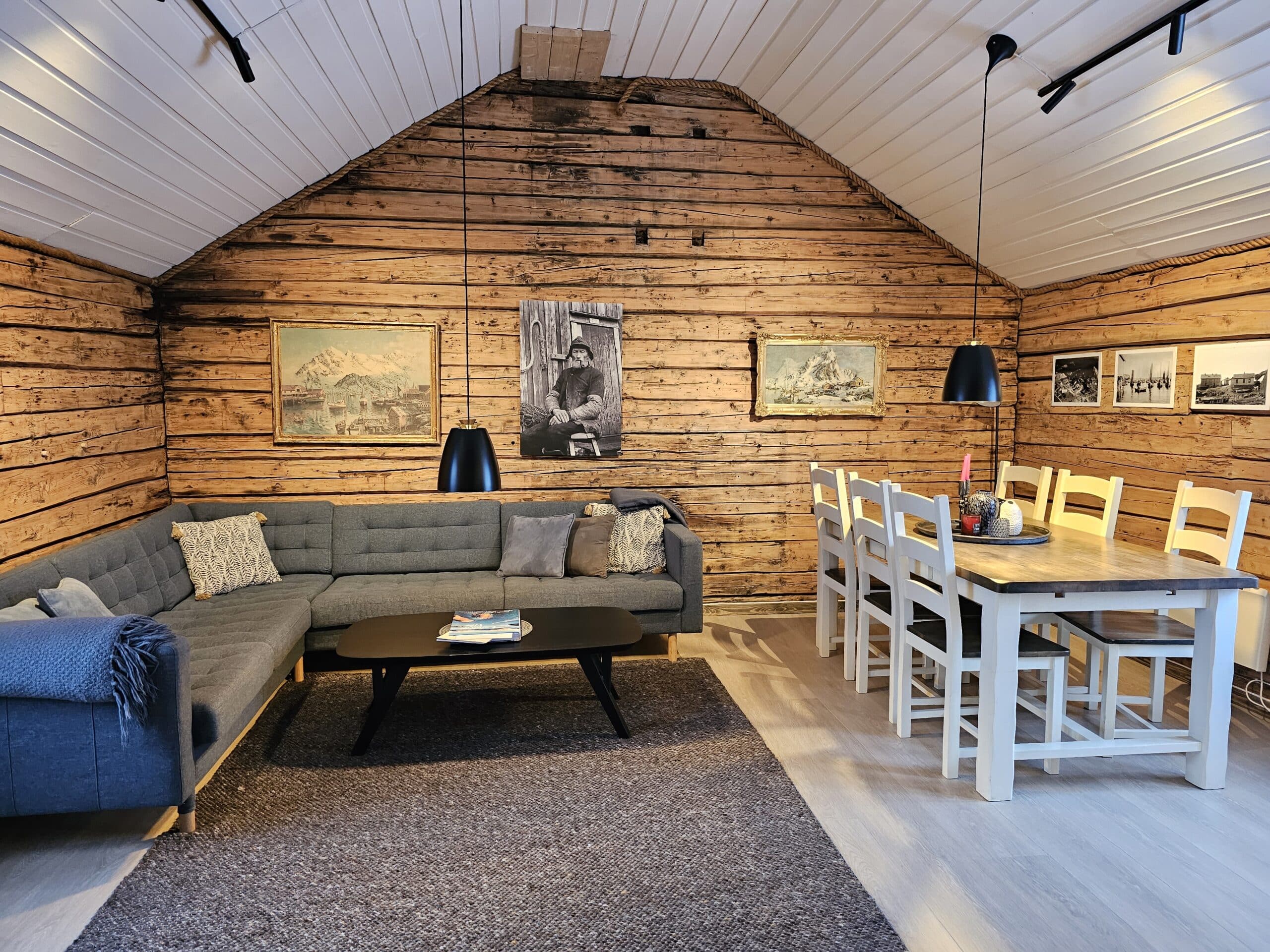 Wooden living room interior with sofa and dining area in a rorbu cabin.